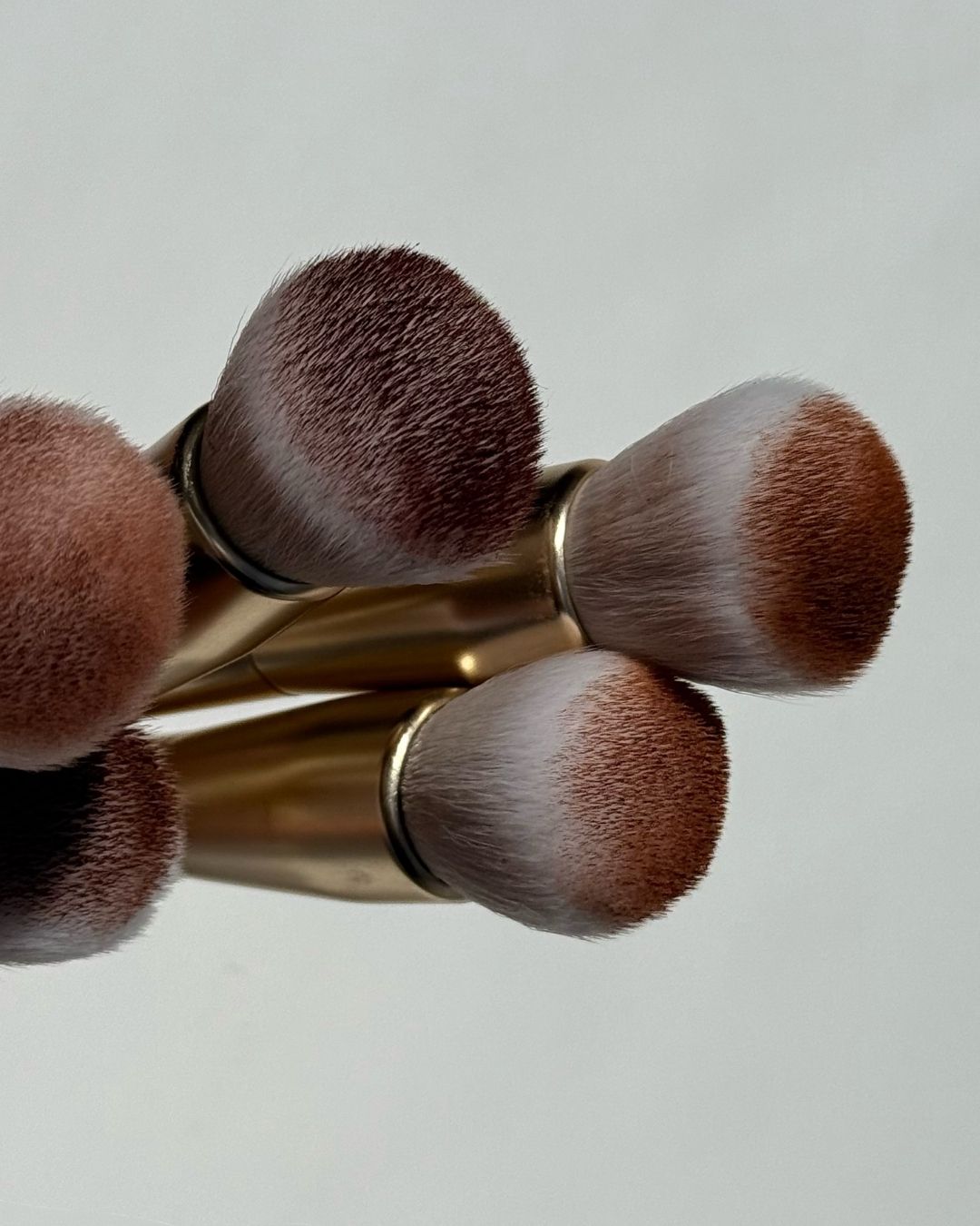 Seint Bronzer brushes, close-up of gold-handled makeup brushes with soft two-tone bristles