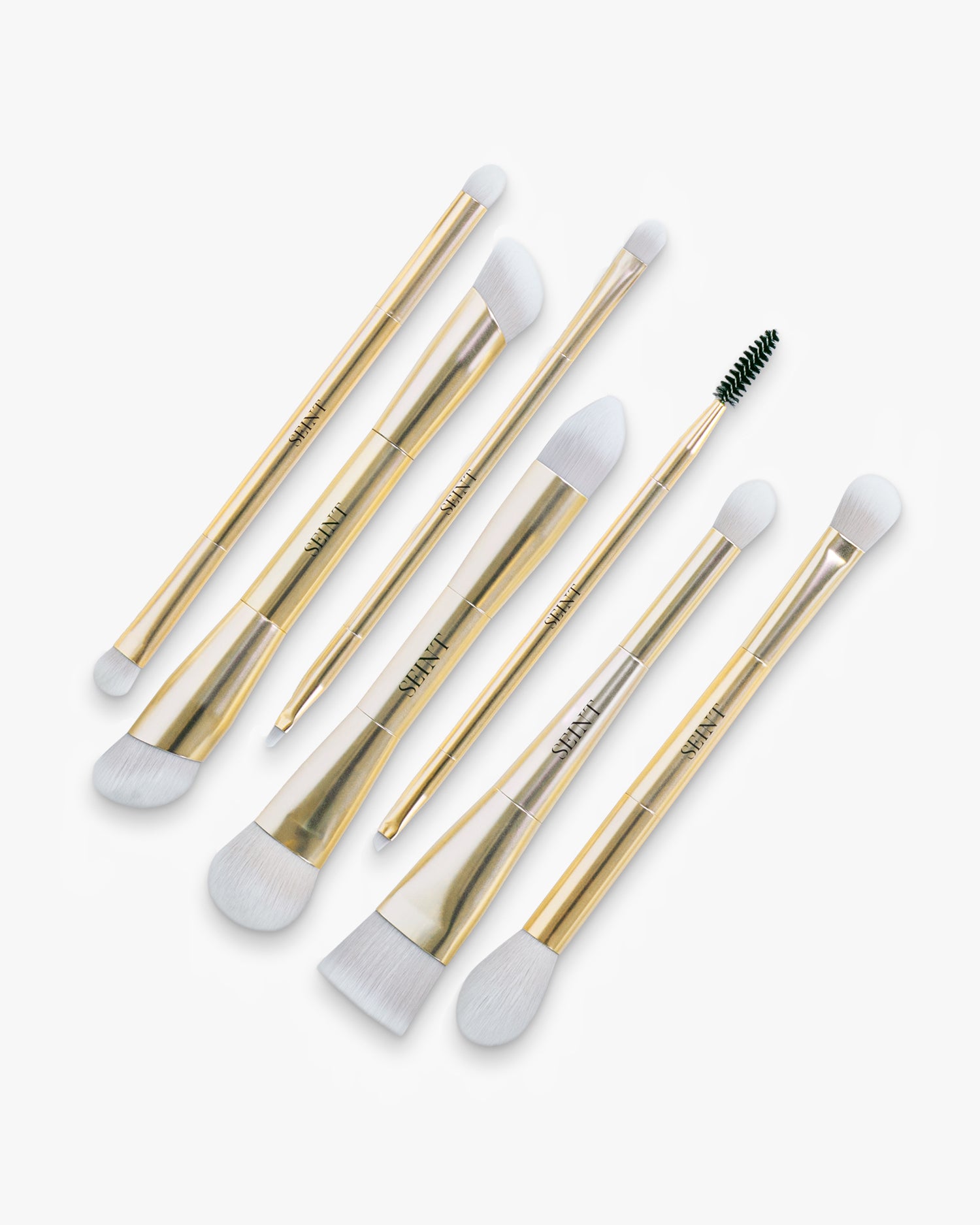 Seint Brush Bundle — seven gold double-ended makeup brushes fanned out, white bristles with one dark spoolie tip