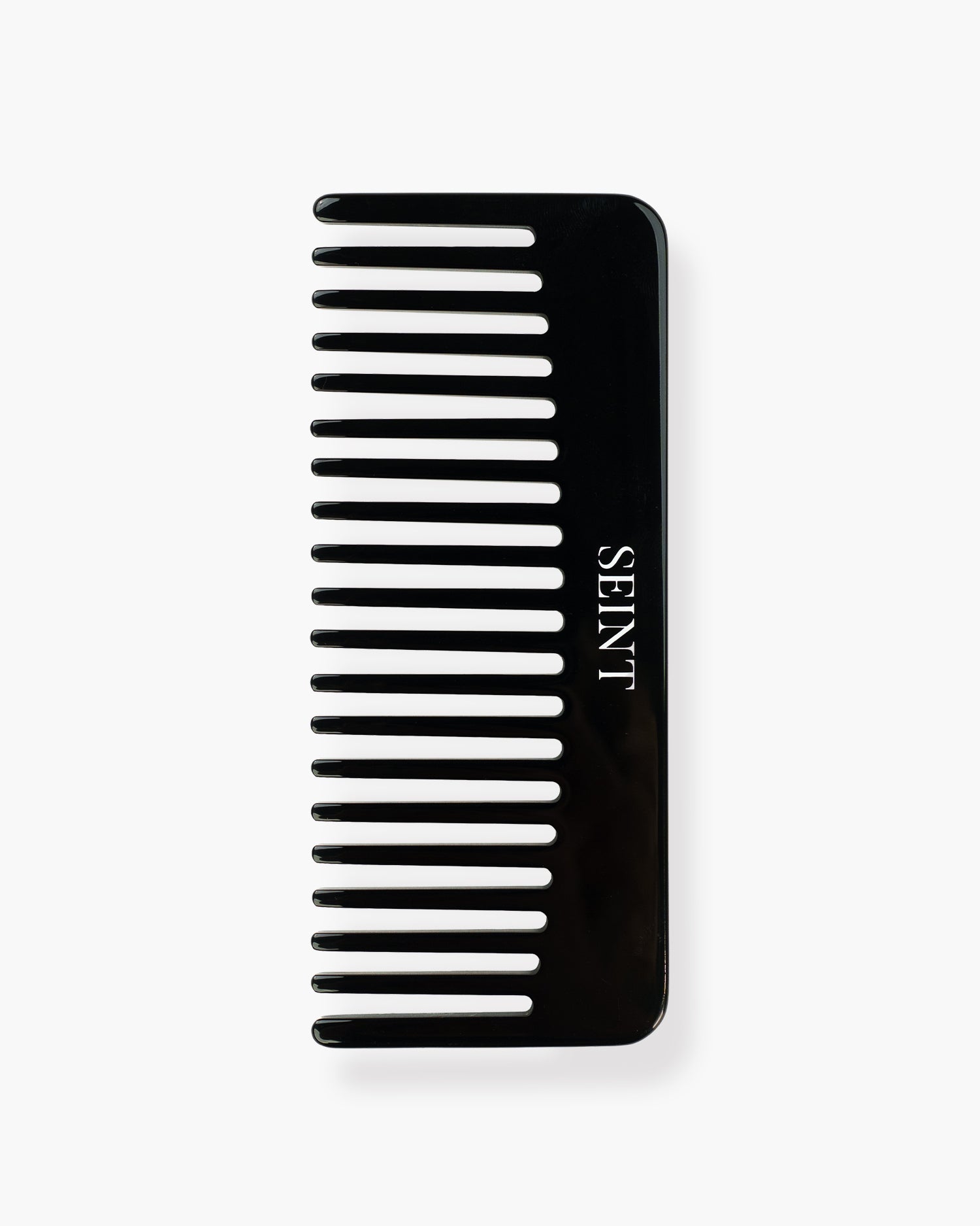 Seint Classic Comb flat lay showing wide glossy black teeth and the SEINT wordmark in white