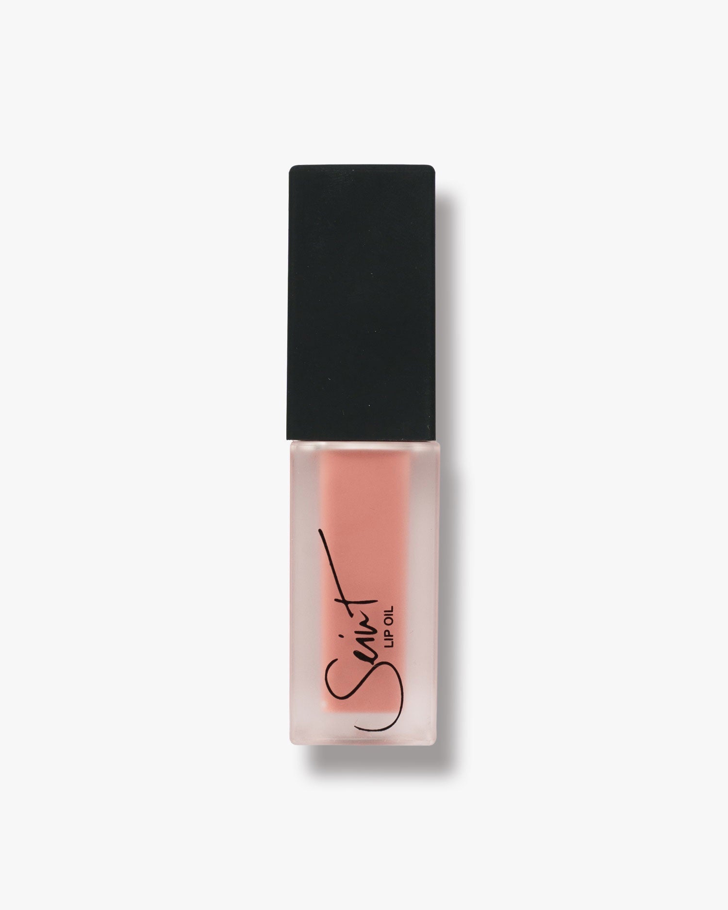 Seint Lip Oil in Desert Sunset, a warm peachy-coral shade in a frosted bottle with black cap