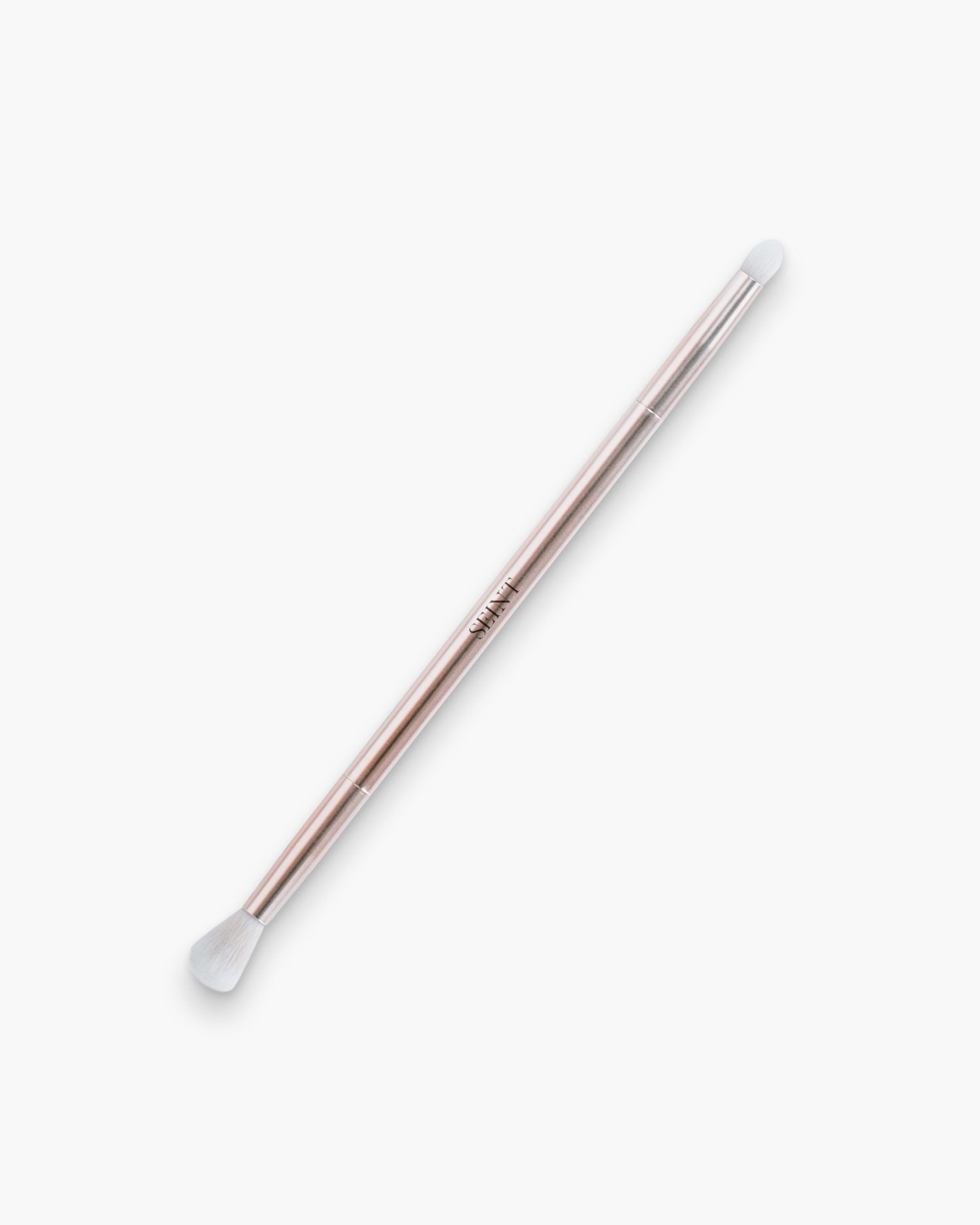 Seint Eyeshadow Brush in rose gold, its soft white bristle tips at each end of the slender metal handle