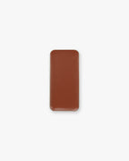 A rectangular pan of brown cream bronzer makeup on a white background.