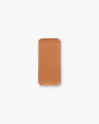 A rectangular pan of orange-brown cream bronzer makeup, set against a white background.