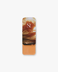 Seint Highlight in Golden Hour, soft amber-orange cream in a tin with sunlit ocean water on the lid