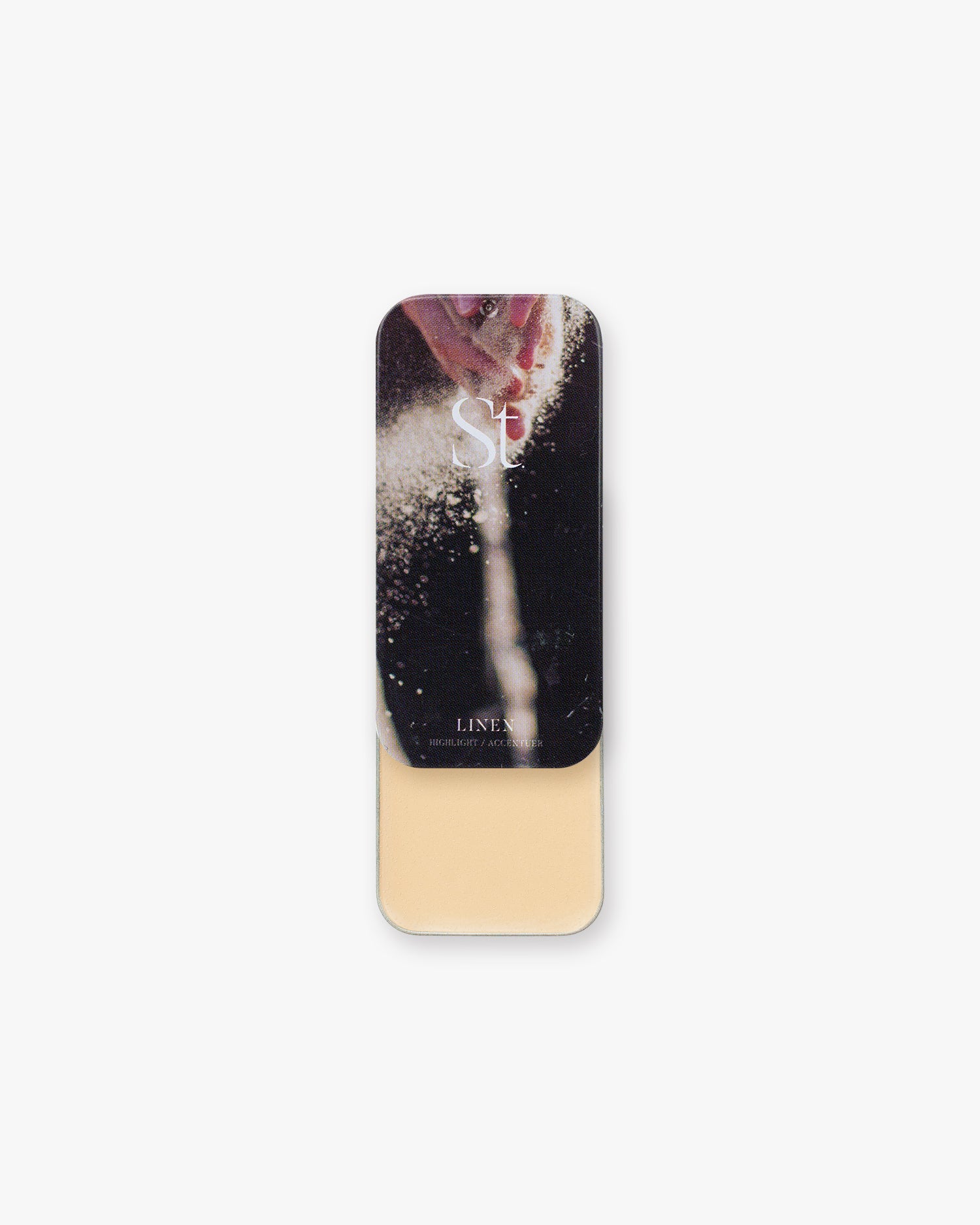 Seint Highlight in Linen, pale warm-ivory cream in a slide tin, lid showing powder sprinkling from a hand