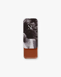 Seint Highlight in Mirage, deep russet-brown cream, lid showing a woman with windblown hair in black and white