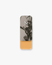 Seint Highlight in Wheat: golden ochre cream in an open tin with an abstract gray botanical lid
