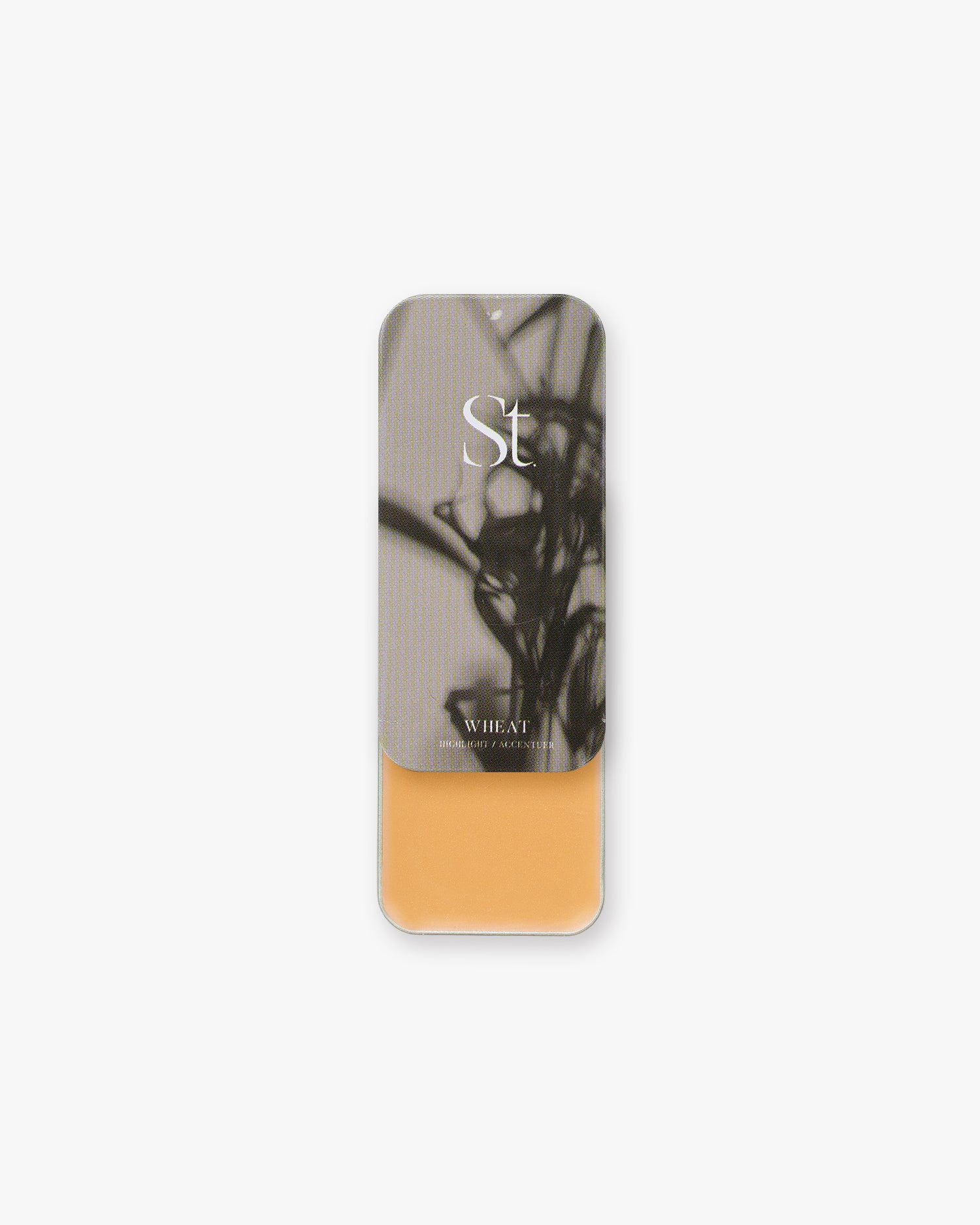 Seint Highlight in Wheat: golden ochre cream in an open tin with an abstract gray botanical lid
