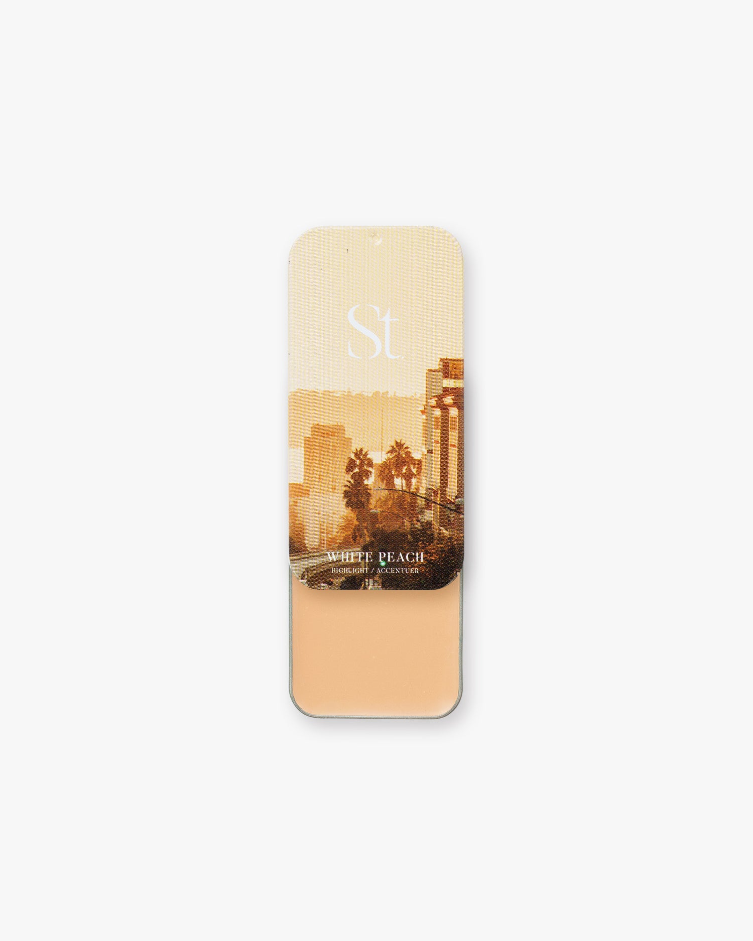Seint Highlight in White Peach: light peach cream in an open tin with a golden palm-lined city street lid