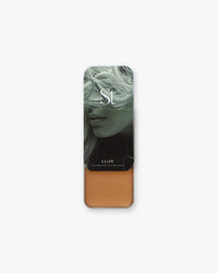 Seint Illuminator in Glow slide-top tin, opened to a warm golden-bronze cream below a green-toned portrait lid