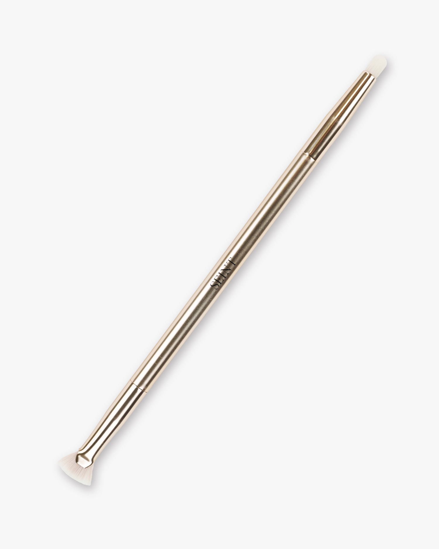 Seint Lash Brush in pale rose gold, its fanned lash end and tapered liner end tipped with soft white bristles