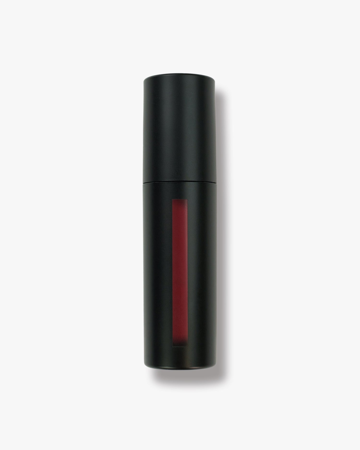 Seint Lip Tint in Poppy shown in a matte black bottle, window strip revealing a warm brick-red tint