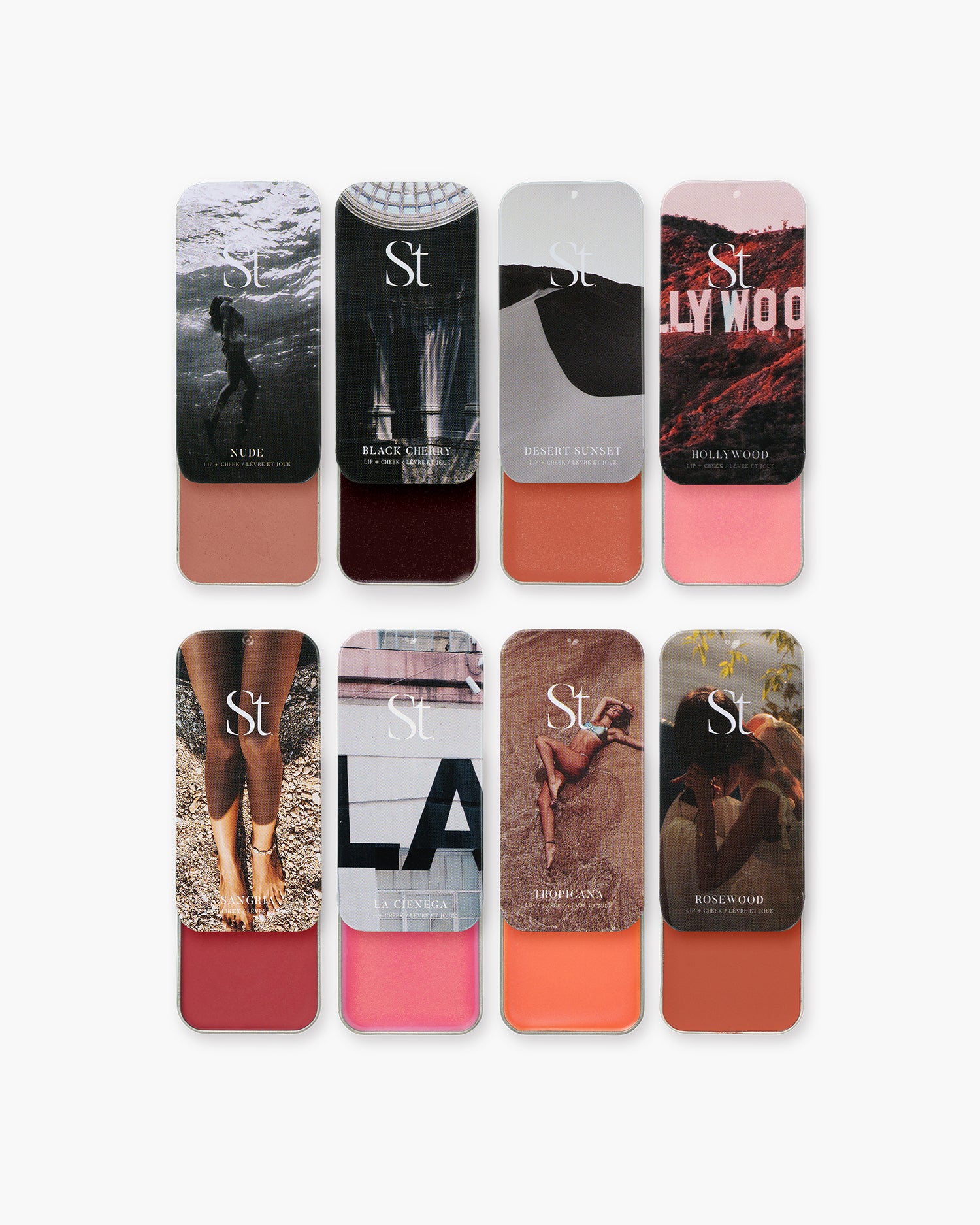 Seint Lip + Cheek Bundle: eight slide tins open, showing creams from soft nude and pink to coral, berry red, and deep cherry