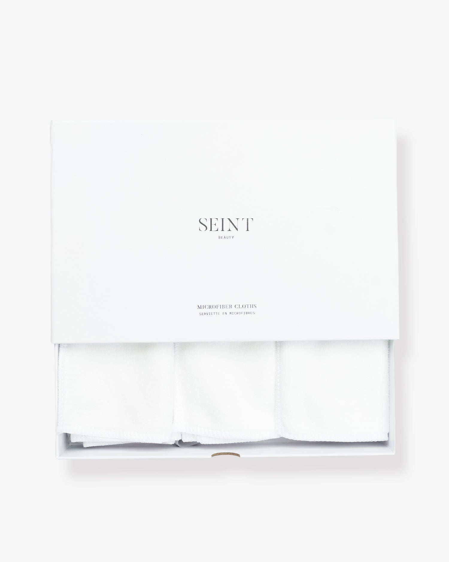 Seint Microfiber Cloths in white — three folded white cloths beneath a lidded box marked SEINT Beauty