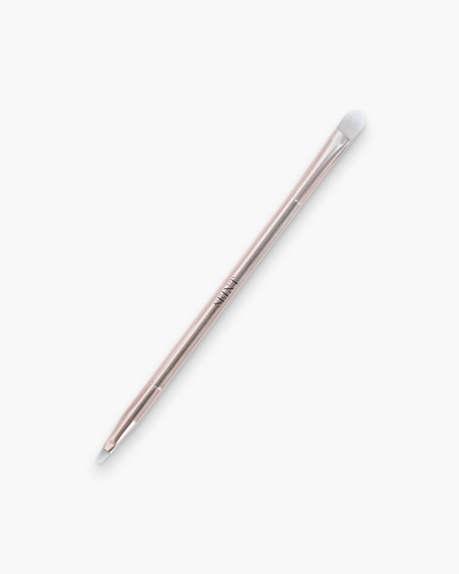 Seint Multitasker Brush with rose gold handle, showing its rounded blending head and small tapered tip