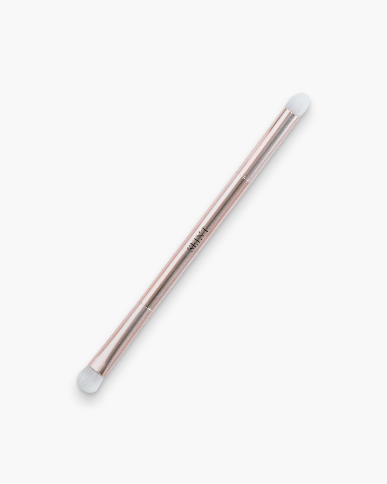 Seint Smudge Brush in rose gold, a two-ended eyeshadow brush with white rounded bristle heads on a slim metallic handle