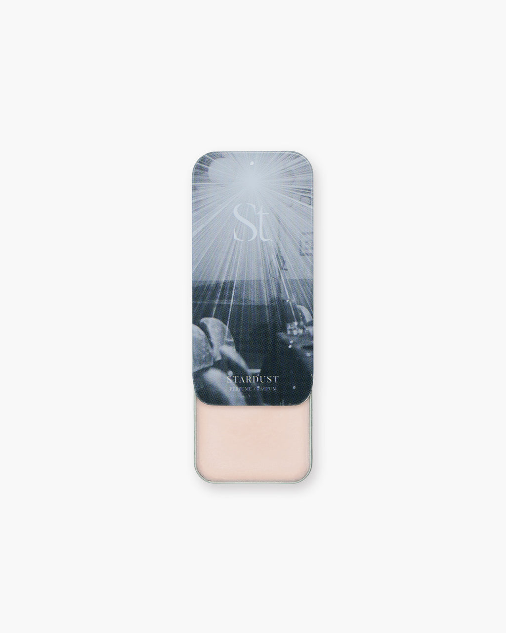 Seint Solid Perfume in Stardust, slide-top tin open to reveal pale pink balm beneath starburst lid art