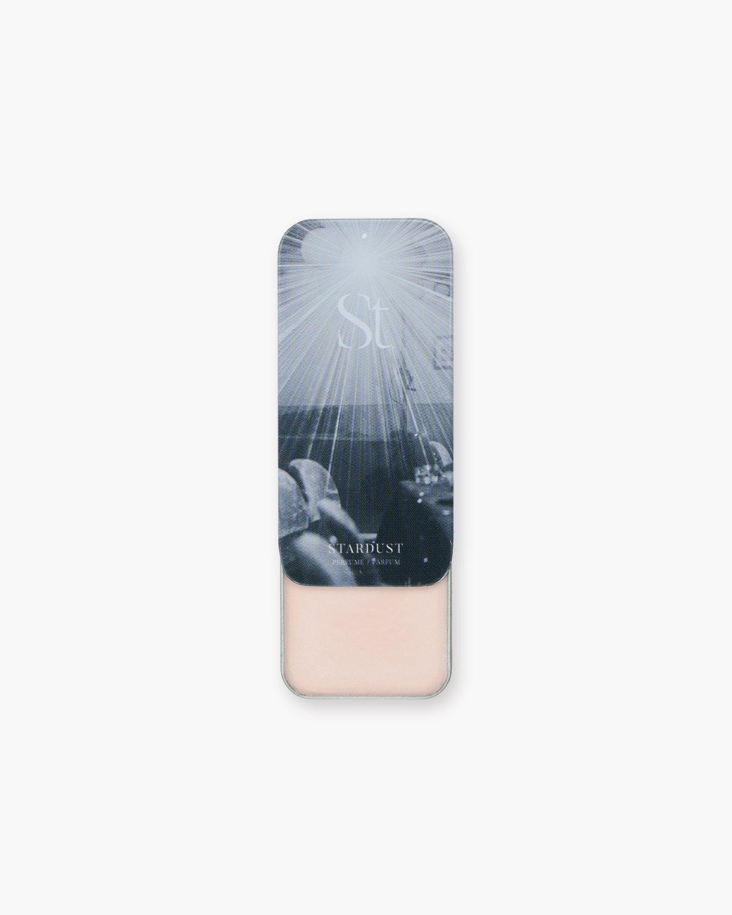 Seint Solid Perfume in Stardust, slide-top tin open to reveal pale pink balm beneath starburst lid art