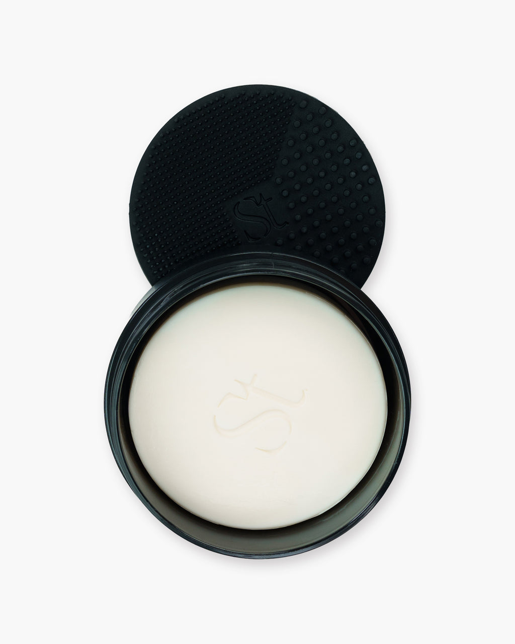 Seint Brush Cleansing Soap opened to show a white soap bar, with the tin's dotted black silicone scrubbing pad behind