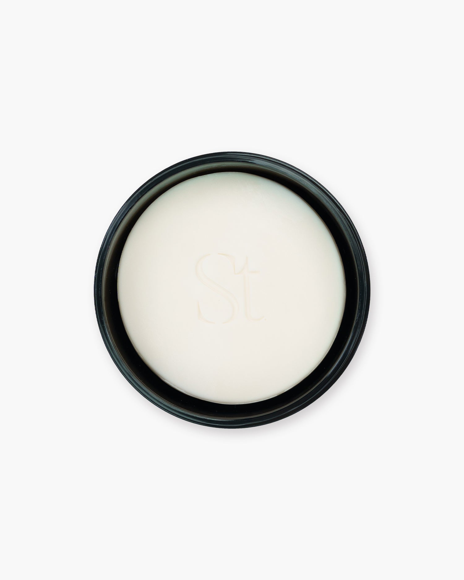 Seint Brush Cleansing Soap bar in creamy white, embossed with the monogram and nested in its open black tin