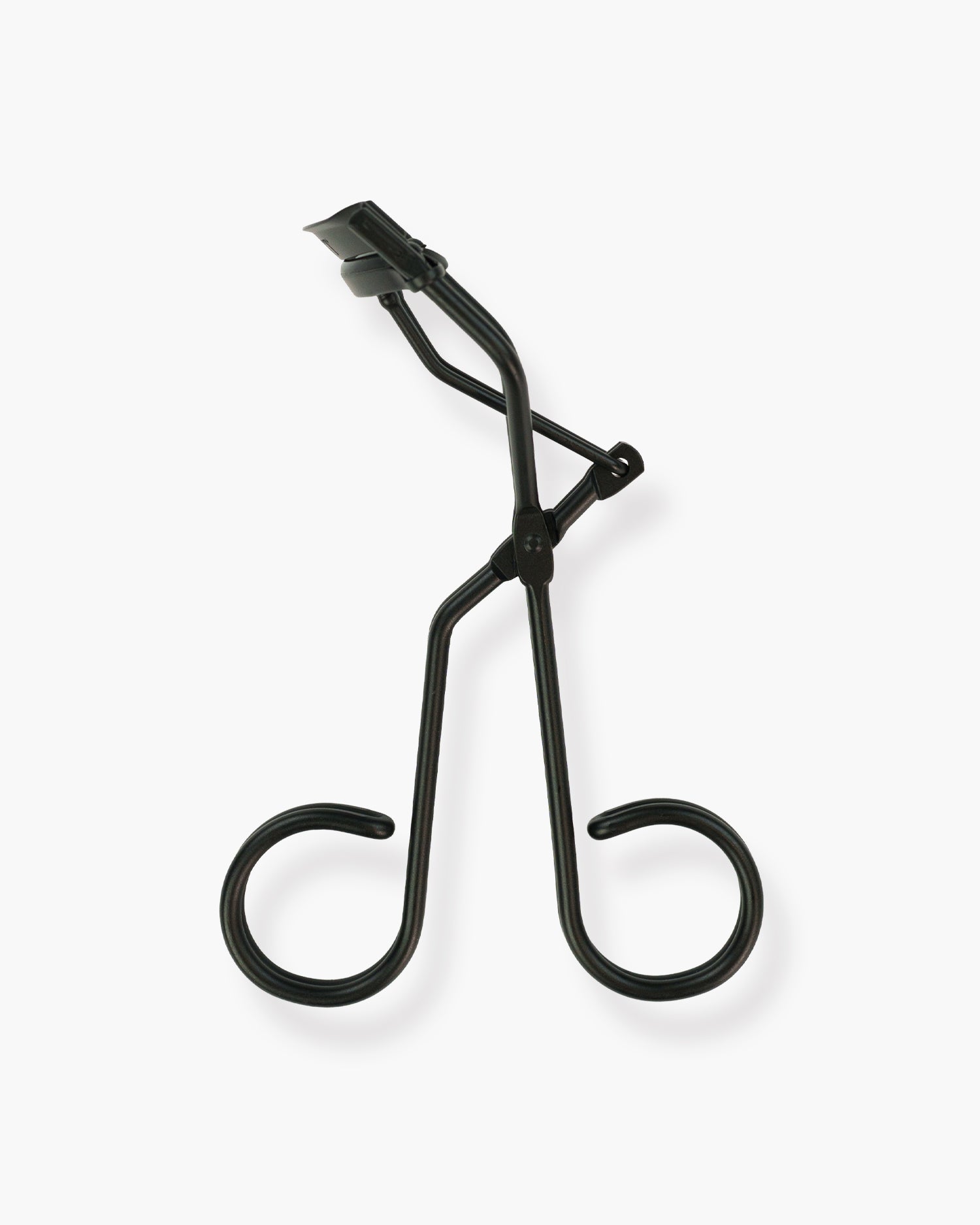 Seint Lash Curler in Crescent — matte black curler with curved pad and looped handles, angled on a white background