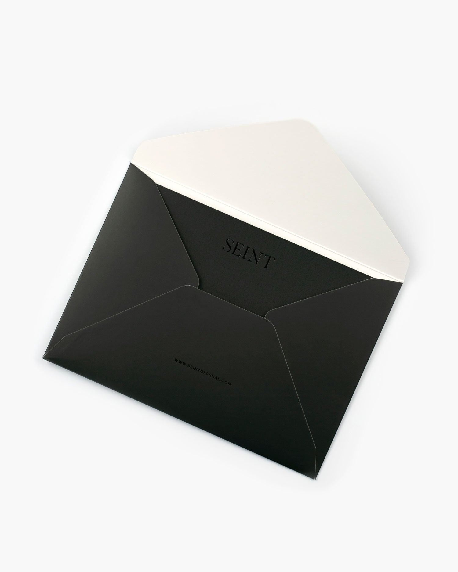 Seint Card + Envelope in Onyx: open black envelope printed with SEINT and seintofficial.com, cream card tucked inside