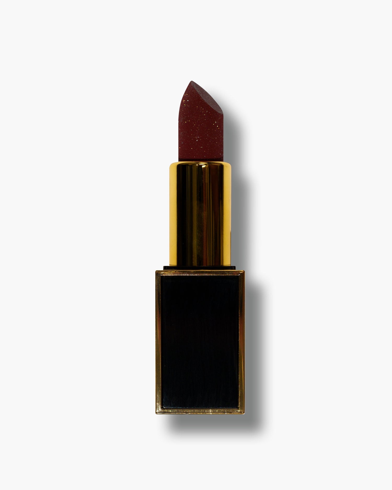 Seint Lipstick in Ever Red, a deep wine-red bullet with subtle gold shimmer rising from its gold and black tube