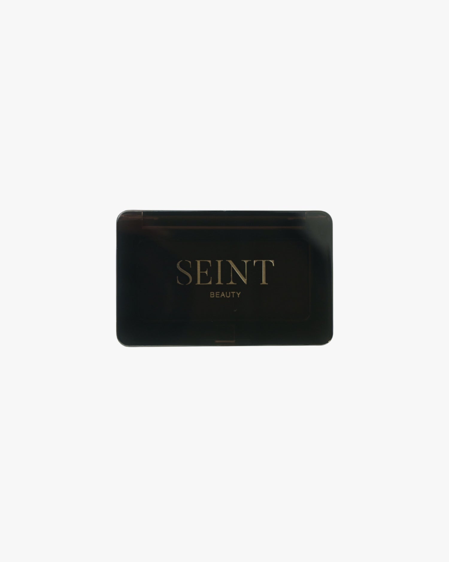 Seint Mini Compact closed, with the gold SEINT Beauty logo on its black lid against a plain white background