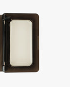 Seint Mini Compact in close-up, lid open with a full-size white cream tin filling the black interior tray