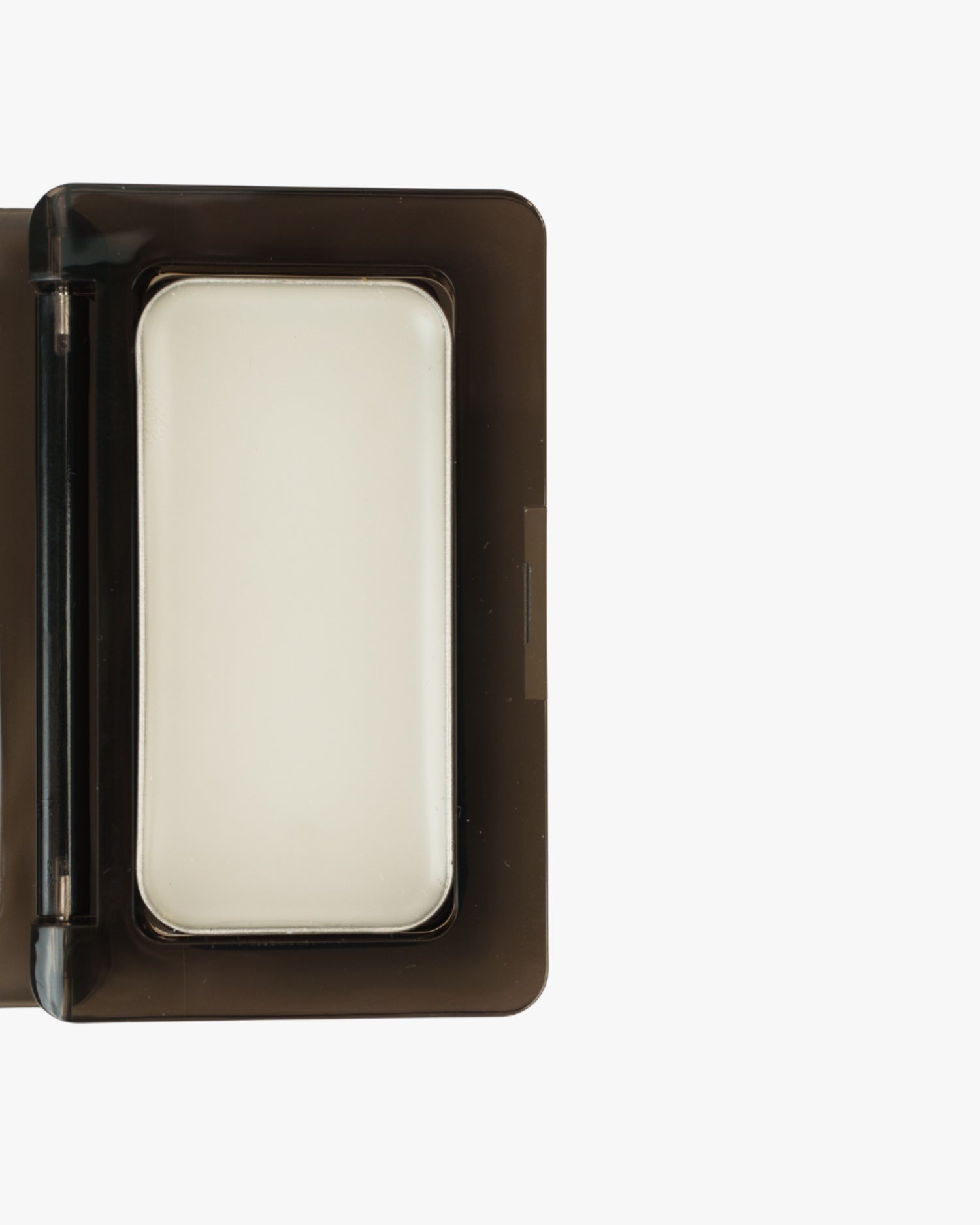 Seint Mini Compact in close-up, lid open with a full-size white cream tin filling the black interior tray