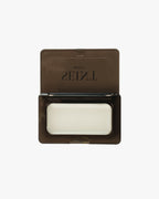 Seint Saved Bundle mini compact open, white lip salve tin inside the smoke-gray case with SEINT lid